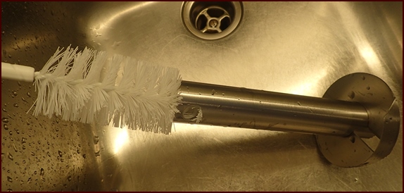 Cleaning inside of pineapple corer with bottle brush.