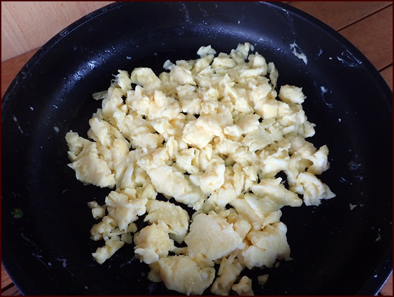 Scrambled eggs cooked in a frying pan.