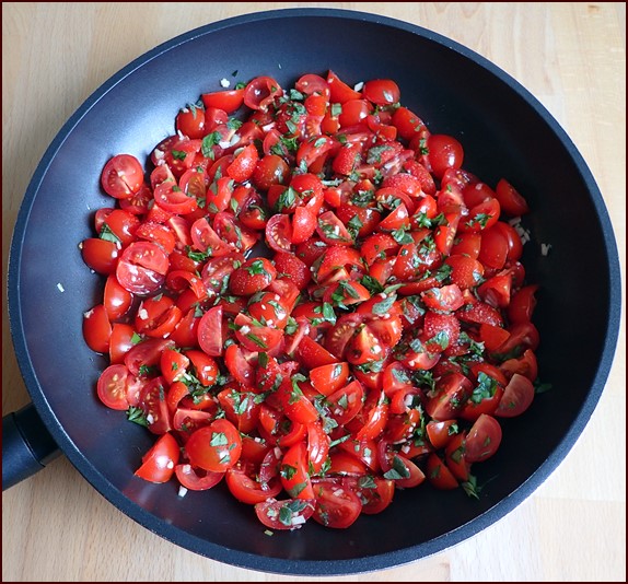 Quartered cherry tomatoes in pan with herbs.