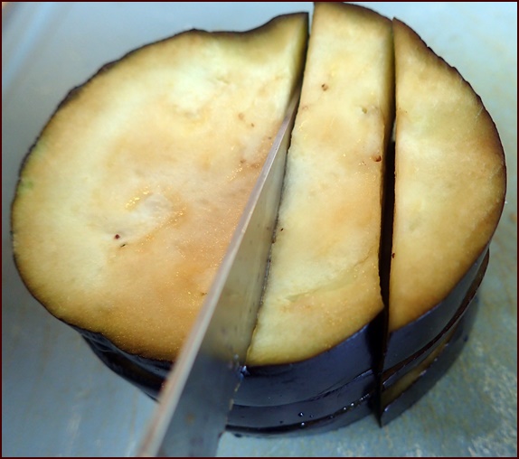 Cutting a stack of eggplant slices.